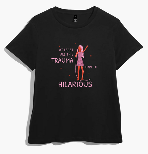 Black women’s t-shirt with a pink-haired singer in a glittery dress and “at least all this trauma made me hilarious” in pink lettering