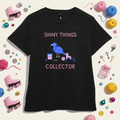 Black women’s t-shirt with a hand-drawn blue bowerbird beside a sourdough jar, yarn, crochet hook and roller skate, with the words Shiny Things Collector in pink